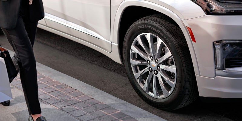 Woman walking by Chevy Traverse parked by curb
